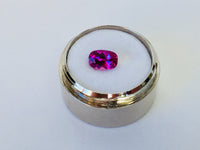 Small rectangle vivid pink sapphire gem, white background, in gem jar.