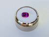 Small rectangle vivid pink sapphire gem, white background, in gem jar.