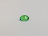 Small cushion shaped bright green tsavorite garnet gem, white background.