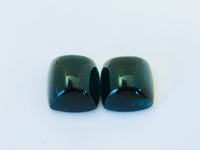 Pair of rectangular deep green blue indicolite tourmaline gems, white background.