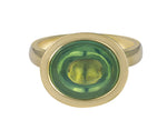 Green gold ring set with upside down large oval cabochon of green zircon. Gem is set in a frame.