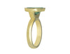 Green gold ring set with upside down large oval cabochon of green zircon. Gem is set in a frame.