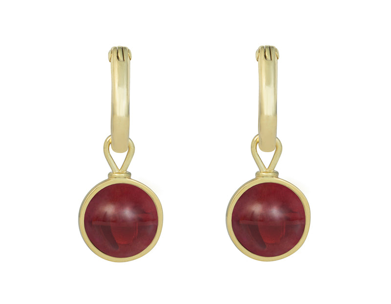 Small round raspberry red drops in green gold frames. Drops hang on small U shaped hoops in solid green gold.