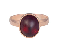 Medium size oval cabochon of raspberry red rhodolite frame set in rose gold ring.