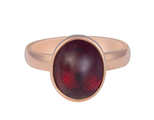 Medium size oval cabochon of raspberry red rhodolite frame set in rose gold ring.