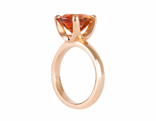 Rose gold ring prong set with oval bright orange citrine. Gem runs parallel to finger.