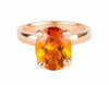 Rose gold ring prong set with oval bright orange citrine. Gem runs parallel to finger.