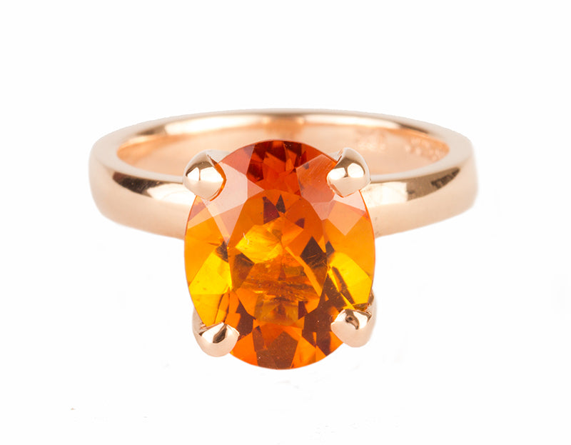 Rose gold ring prong set with oval bright orange citrine. Gem runs parallel to finger.