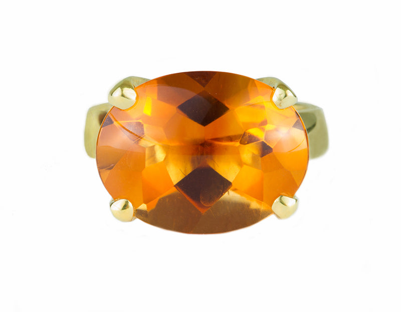 Large bright orange oval citrine set in robust prongs in green gold ring.