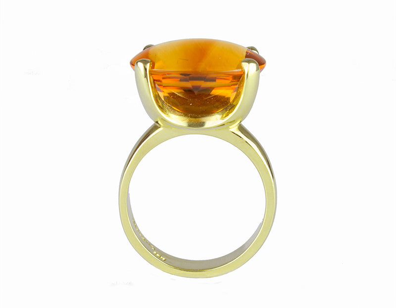 Large bright orange oval citrine set in robust prongs in green gold ring.
