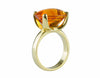 Large bright orange oval citrine set in robust prongs in green gold ring.
