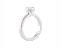 Platinum ring set with round pastel blue sapphire.  The gem is bezel or frame set and sits above the band.