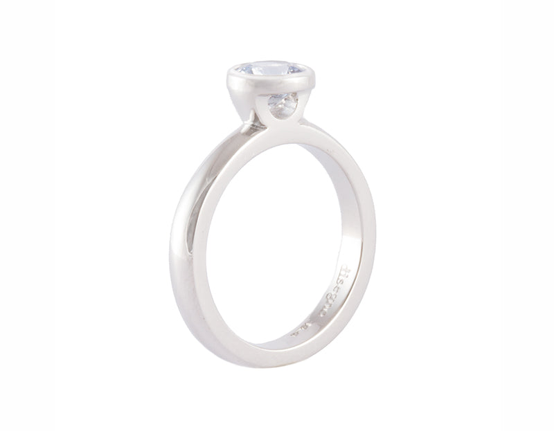 Platinum ring set with round pastel blue sapphire.  The gem is bezel or frame set and sits above the band.
