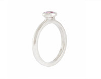 Thin platinum ring set with round pink spinel.  the gem is set in a frame and sits above the band.