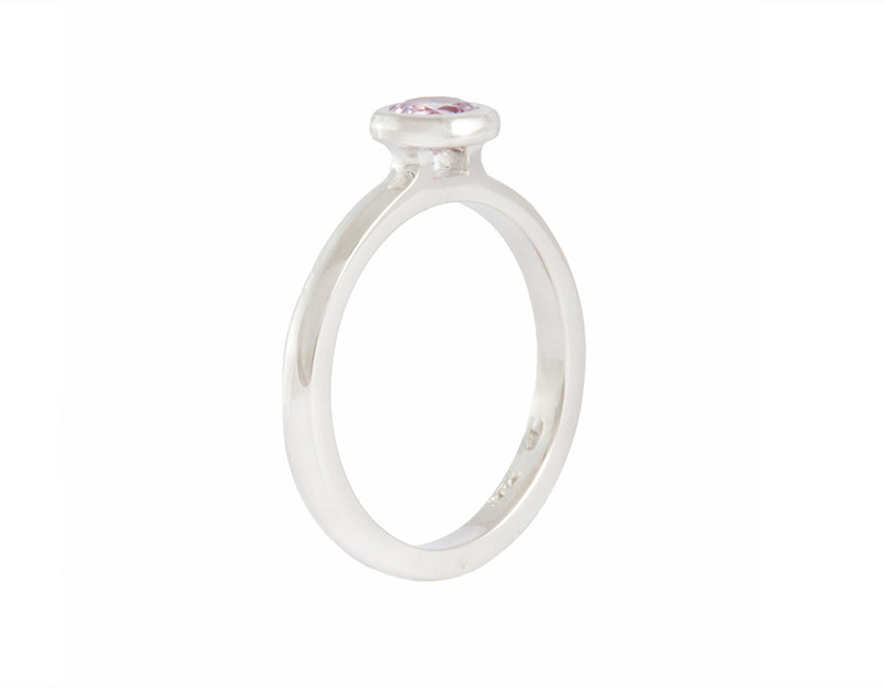 Thin platinum ring set with round pink spinel.  the gem is set in a frame and sits above the band.