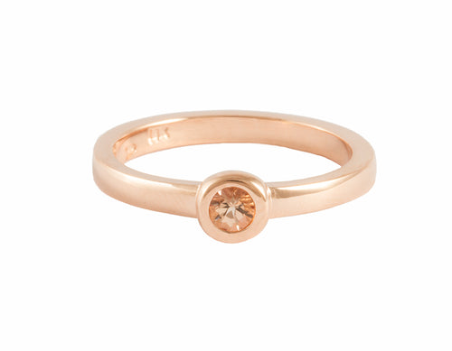 Thin rose gold ring set with a peach or flesh colour topaz. The gem is bezel set and sits right on top of the band.