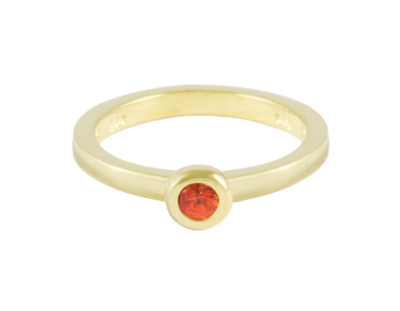 Thin green gold ring set with a bright orange sapphire. Gem is set in a frame.