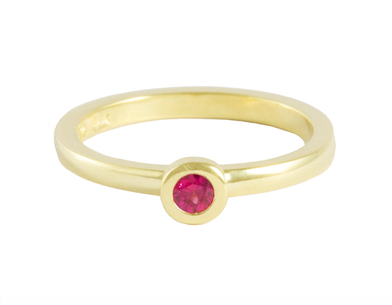 Thin green gold ring set with a bright pink sapphire. Gem is set in a frame.
