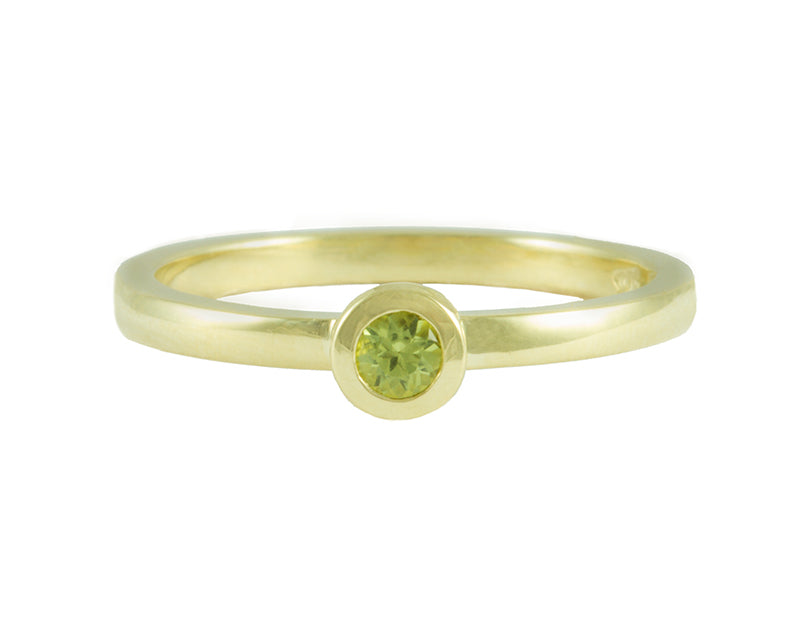 Thin 18 karat green gold band with soft matte finish set with bright green round peridot. Gem set in a frame that sits on the band.