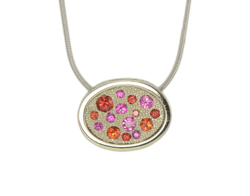 White gold pendant, round face, small pink, orange, reddish gems scattered in the face.