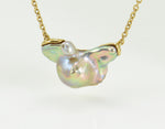 Large free form pearl set in yellow gold and yellow gold chain.