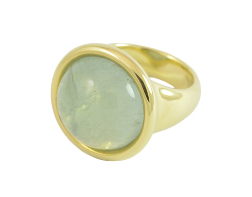 Very large green gold ring set with large round cabochon of blue aquamarine. Gem is set in frame and goes beyond width of finger.