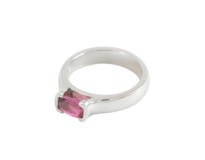 Platinum ring with oval deep pink sapphire bezel set at two ends.