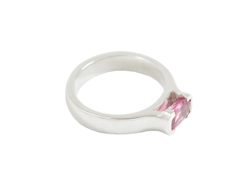 Platinum ring with oval deep pink sapphire bezel set at two ends.