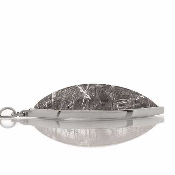 Very long clear gem pointed at two ends illed with black crystal threads in white gold.