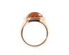 Rose gold ring set with medium oval cabochon of bright orange spessartite garnet. Gem is set in frame and lies across the finger.