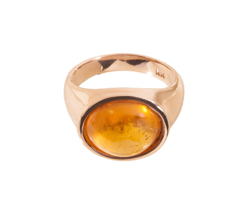 Rose gold ring set with medium oval cabochon of bright orange spessartite garnet. Gem is set in frame and lies across the finger.