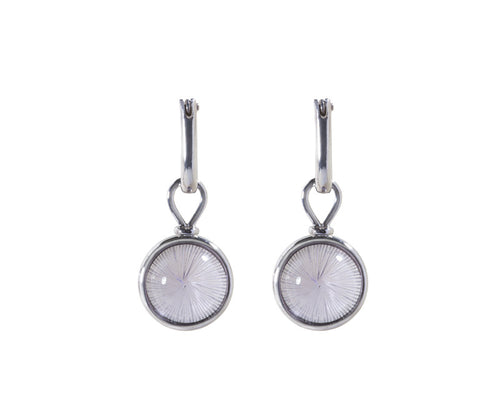Round drops with light purple cabochon gems, carved with thin radiating lines from centre in white gold frame. Drops hang on small U shaped hoops in solid white gold.
