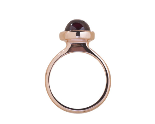 Medium size round cabochon of raspberry red rhodolite frame set in rose gold ring.