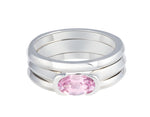 Platinum ring with natural pink sapphire, stacked with two matching platinum bands. The sapphire is oval and lies across the finger and is bezel set at two ends.