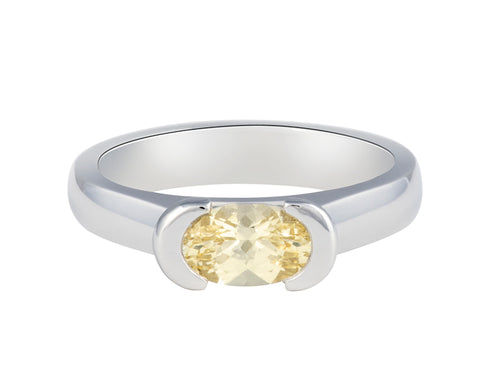 Platinum ring with natural pastel yellow sapphire. The sapphire is oval and lies across the finger and is bezel set at two ends.