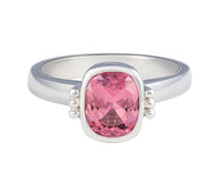 Platinum ring with natural pink spinel.  The gem is rectangular, lies parallel to finger, cut with a checkerboard pattern and surrounded by a frame, that is, bezel set.  Gem setting is raised above the ring.