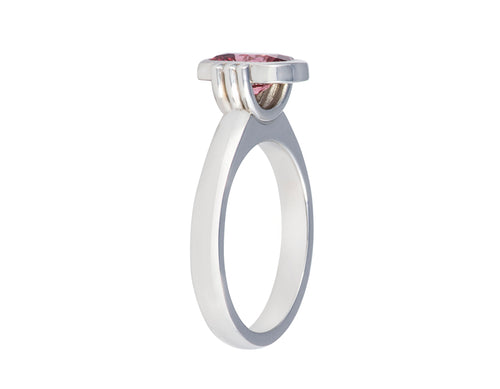 Platinum ring with natural pink spinel.  The gem is rectangular, lies parallel to finger, cut with a checkerboard pattern and surrounded by a frame, that is, bezel set.  Gem setting is raised above the ring.