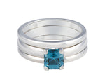 Platinum ring set with medium blue spinel with a pair of matching platinum bands.  The spinel is rectangular and prong set and sits above the band.