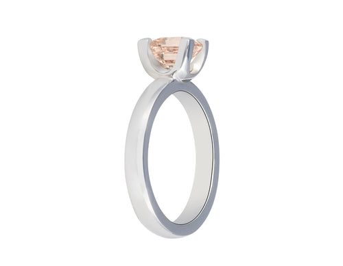 Platinum ring with prong set natural peach coloured sapphire. Sapphire is slightly rectangular and lies parallel to the finger.