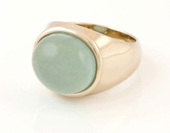 Large green gold ring set with medium oval cabochon of blue aquamarine. Gem is set in frame and lies across the finger.