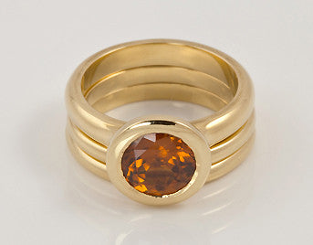 Round orange gem set in yellow gold with matching yellow gold bands.