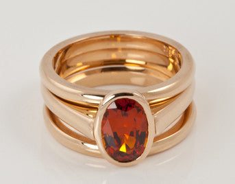 Oval orange gem set in rose gold with matching rose gold bands.