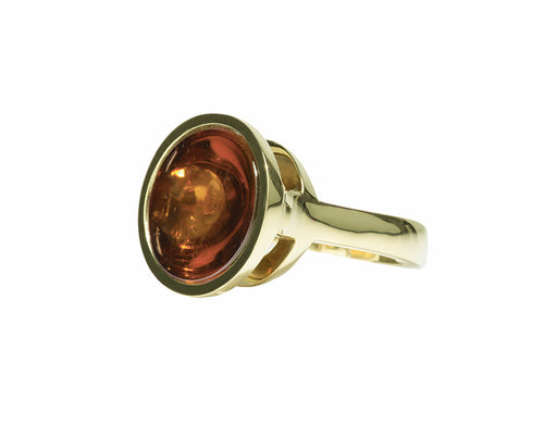 Large green gold ring with large golden brown cabochon gem upside down.