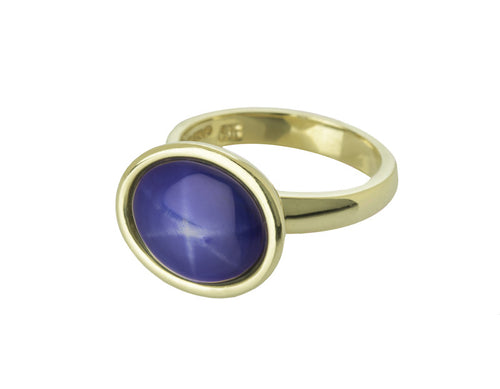Blue star sapphire cabochon gem in green gold ring.